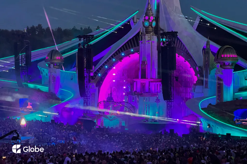 Tomorrowland's mainstage lit up in purple and pink, with a massive crowd dancing below at night