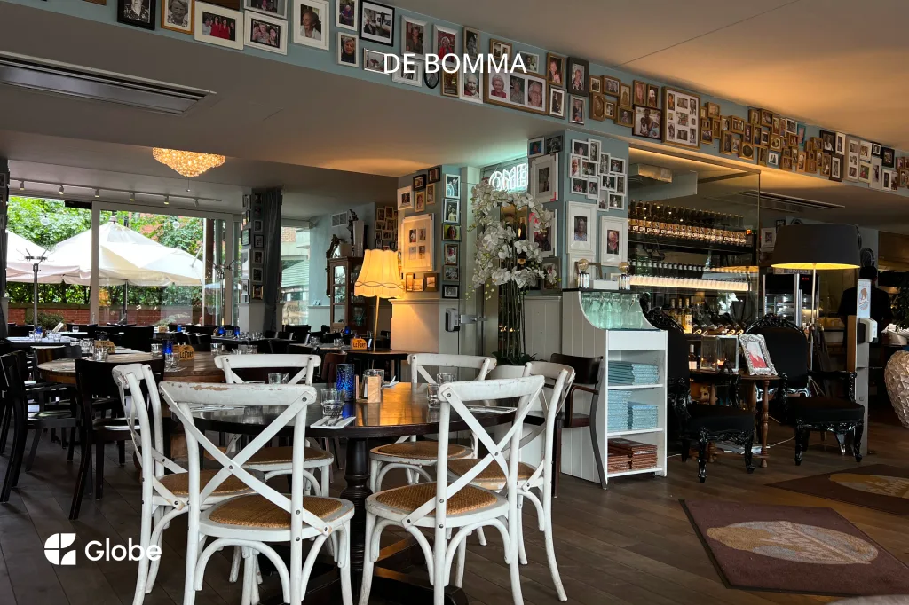The dining room at De Bomma restaurant in Antwerp, with white chairs and walls covered in framed photos