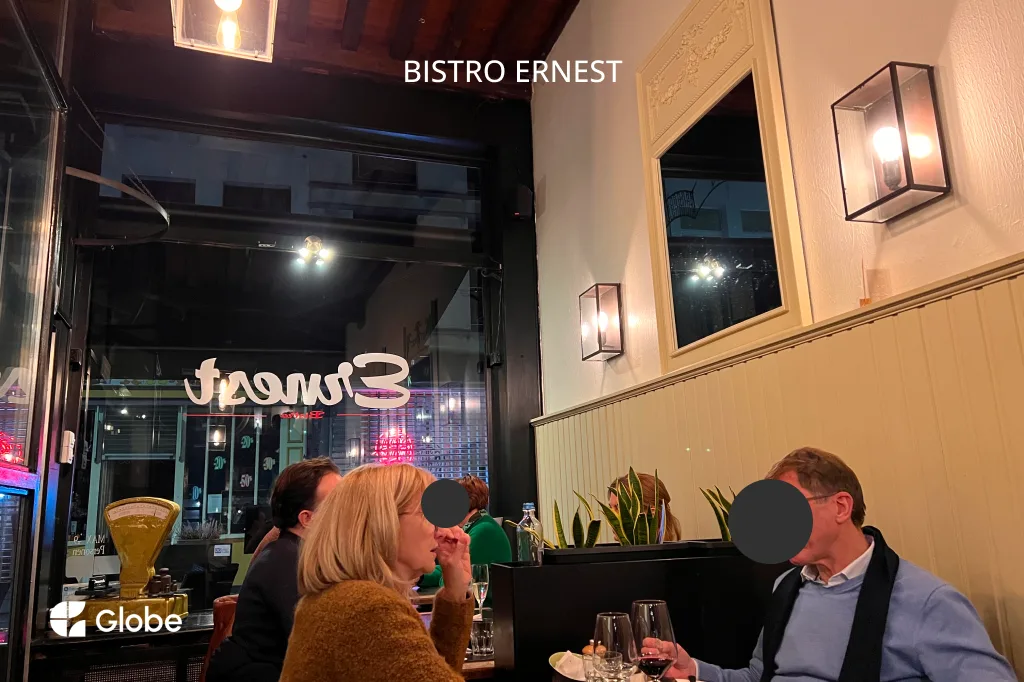 The warmly lit interior of Bistro Ernest in Antwerp, with diners seated at a table by the window
