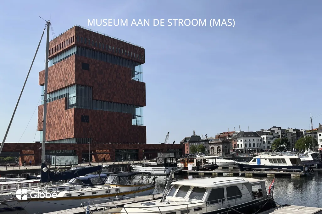 MAS museum's stacked red sandstone tower overlooking the Antwerp harbor with boats docked in front